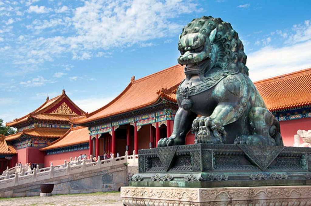 Giant statue of a lion in front of traditional houses in China.